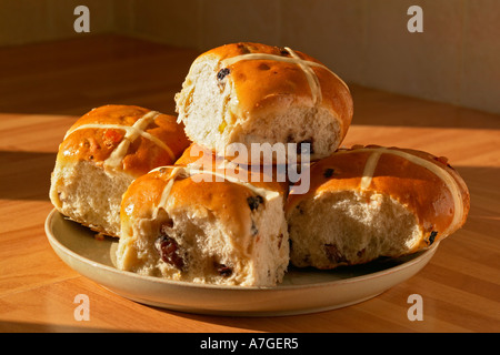 five hot cross buns on a plate in evening light Stock Photo