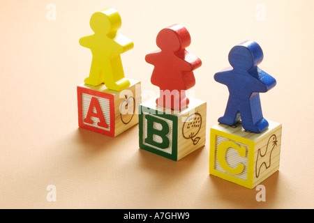 Wooden Children Figurines Standing on Alphabet Blocks Stock Photo