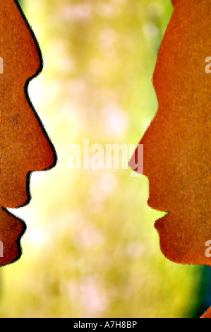 Two faces art statue in Keukenhoff garden near Lisse Holland. Rusty metal silhouettes of human profiles facing each other in a blurred garden. Stock Photo
