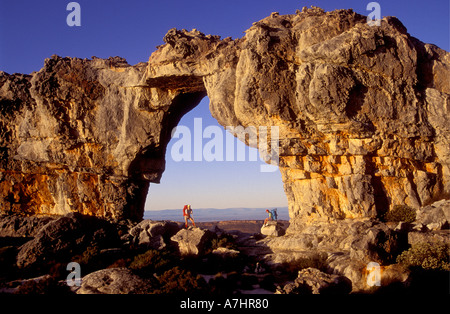 Hiker standing in the Wolfberg Arch Cederberg Mountains Western Cape South Africa A second hiker is seated under the arch Stock Photo