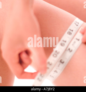 A young woman measuring her thigh Stock Photo