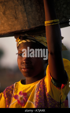 Peul girl carrying her dishes to wash in the river, Djenné, Mali Stock Photo