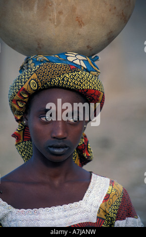 Peul girl with characteristic mouth tattoo carrying water, Djenné, Mali Stock Photo