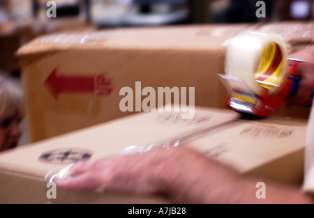 Warehouse worker taping cardboard boxes Stock Photo