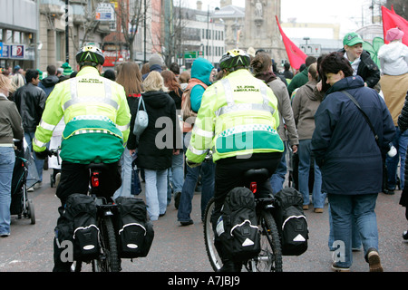 Two St John ambulance bicycle personnel on duty follow the St Patricks Day Parade Belfast Northern Ireland Stock Photo