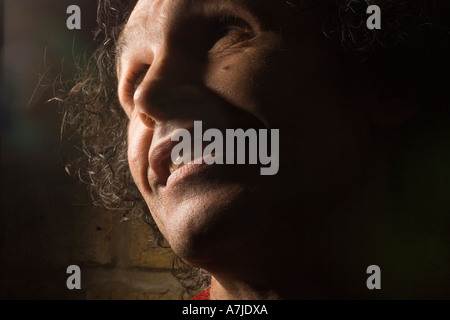 Portrait of a middle-aged man with a mocking expression, half of his face hidden in darkness, keith richard double Stock Photo