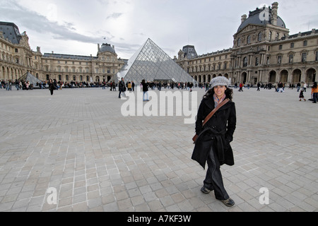 Female visitor outside of the Louvre, Paris, France, with pyramid in background. Stock Photo