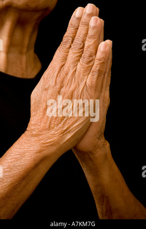 An old asian woman holds her hands in prayer Stock Photo