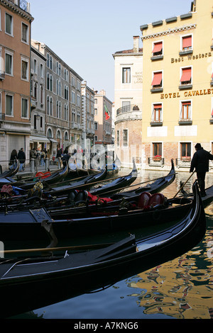 Venetian gondolas wait outside a top central hotel for rich tourist passengers to take boat trips Venice Italy Europe EU Stock Photo