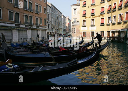 Venetian gondolas wait outside a top central hotel for rich tourist passengers to take boat trips Venice Italy Europe EU Stock Photo