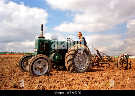 An old fashioned vintage working tractor ploughing a field Stock Photo