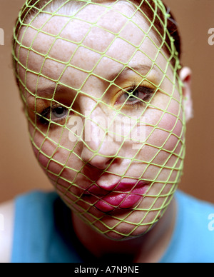 indoor studio woman young girl 20 25 make up eye shadow eye shadows yellow lipstick pink shirt blue net mesh meshes close up Stock Photo