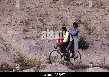 Mexico Chihuahua State Three Tarahumaran Indians Boys Riding One Bike On A Countryside Road Near Creel In The Copper Canyon Stock Photo