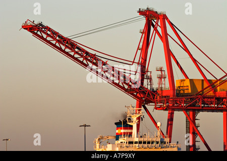 Container crane lifting portainer shipping container from cargo ship ...