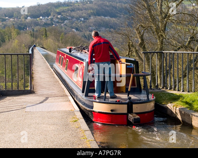 A man steers a red tourist narrow boat on to the Pontcysyllte aqueduct at Trevor Denbighshire Wales Stock Photo