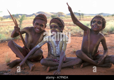 Happy Aboriginal boys painted up for ceremony play with boomerang in the desert south of Alice Springs Central Australia Stock Photo