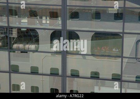 Cruise ship Aurora reflected in the windows of the cruise terminal building in Amsterdam, Netherlands Stock Photo