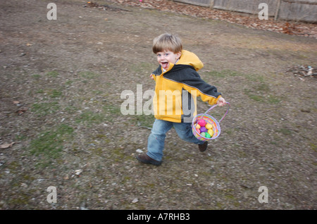 Small child with easter basket looking for easter eggs in a backyard easter egg hunt Stock Photo