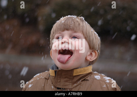 Small boy catching snow flakes on tongue during winter snow Stock Photo