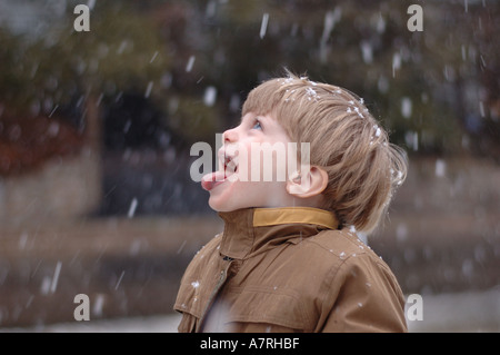 Small boy catching snow flakes on tongue during winter snow Stock Photo