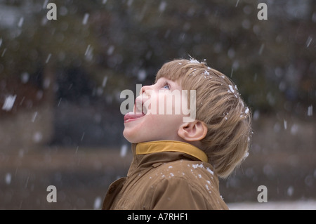 Small boy catching snow flakes on tongue during winter snow Stock Photo