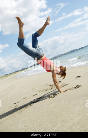 Side profile of woman doing cartwheel on beach Stock Photo