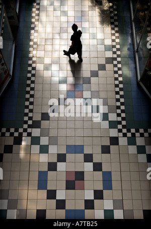 Lone male figure in silhouette walking on tiled floor in Barton Arcade Manchester seen from above Stock Photo
