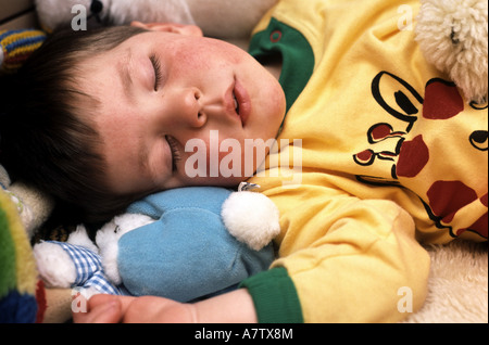 two year old boy suffering from eczema sleeping with toys Stock Photo