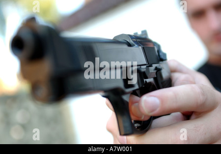 a man pointing a gun ready to fire beretta automatic pistol Stock Photo