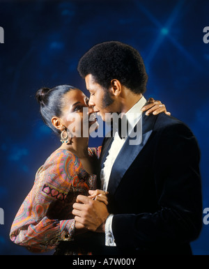 1970s AFRICAN AMERICAN COUPLE MAN TUXEDO WOMAN EVENING DRESS DANCING EMBRACING Stock Photo