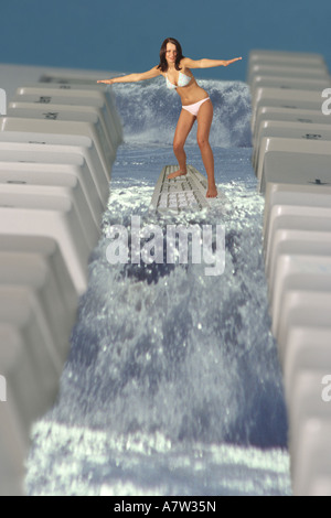 Young Woman using computer keyboard as a surf board Stock Photo