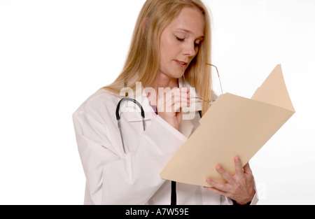 Caucasian female general practitioner looking down while writing notes in patient’s folder at medical office, USA. Stock Photo