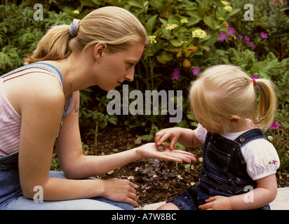 Mother showing a toddler a snail in the garden Stock Photo