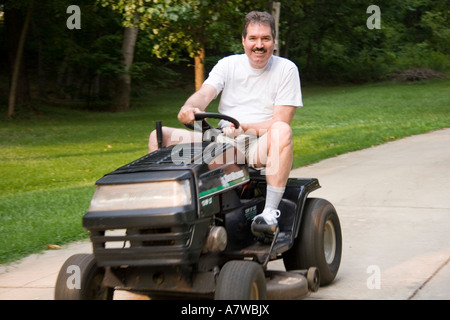 Man on riding lawn mower Stock Photo