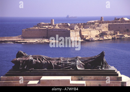 MALTA. Part of the Siege Bell Memorial in Valletta, with Ricasoli Fort and the entrance to the Grand Harbour behind. Stock Photo