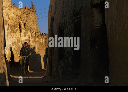 Egypt, El Bawati, Man rides bike down alley Stock Photo