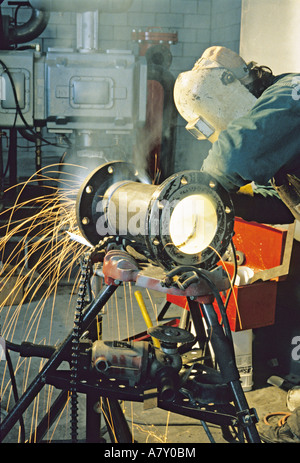 Pipe fitter grinding pipe in factory construction site. Stock Photo