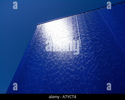 Water running down the surface of building covered in blue painted metal plates Stock Photo