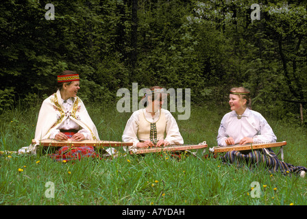 Three Latvian girls dressed in traditional clothes playing kokles at a music festival Stock Photo