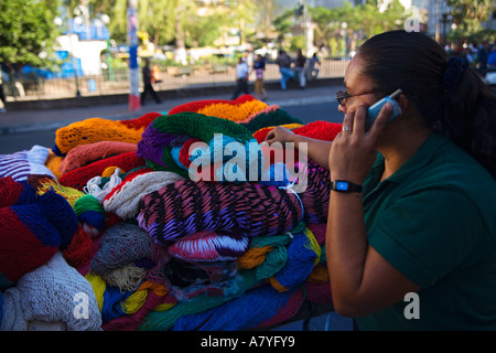 Lady street vendor on mobile phone whilst selling her knit-wear in San Salvador city Republic of El Salvador Central America Stock Photo