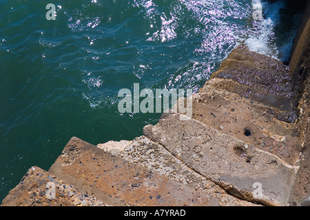 Old stone steps leading from jetty down to sea Stock Photo