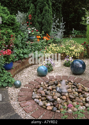 Domestic back garden  mixture summer bedding perennial plants & small water feature in area previously occupied by fish pond Stock Photo