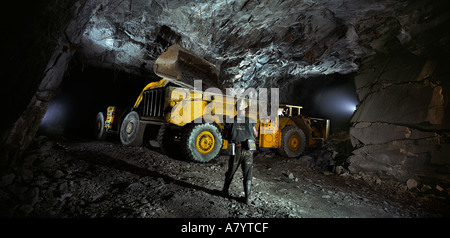 Mining operations for transporting, managing & the processing of gold ore. Front end loader underground in gold mine moving ore to conveyor.  Ghana Stock Photo