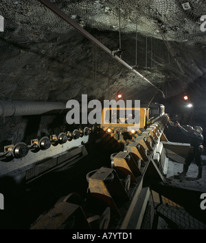 Mining operations for transporting, managing & the processing of ore. Mined ore taken for processing by narrow gauge underground train in gold mine . Stock Photo