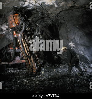 Mining operations for transporting, managing & the processing of gold ore. Mine geologist supervising core sample drill in underground gold mine Ghana Stock Photo