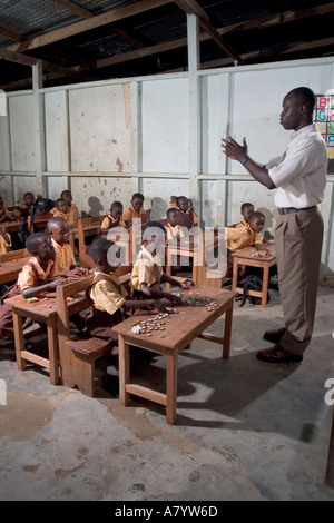 Inside classroom of mixed group of young girls and boys junior school children in maths class, using bottle tops as counters, in Ghana, West Africa Stock Photo