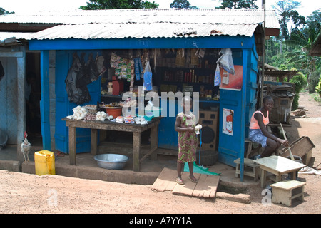 Woman shopkeeper cooking the family lunch with her daughter nearby and outside her general store in Western Ghana Stock Photo