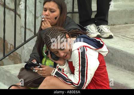 Girls age 16 talking on cell phones and smoking  at Cinco de Mayo Festival. St Paul Minnesota USA Stock Photo