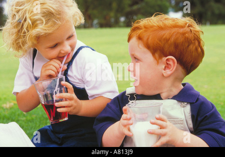 portrait of blond girl and red-headed boy drinking milk and juice