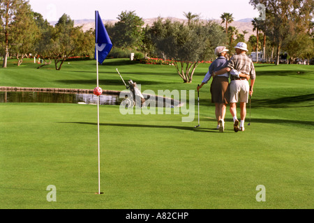 Senior couple in 70's walking off putting green together on golf course in Palm Springs, California Stock Photo